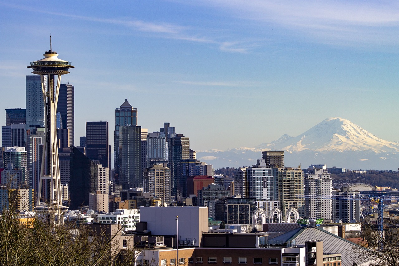 Seattle skyline in the daytime with the Needle on the left hand side and a view of Mt. Rainier in the background on the right.